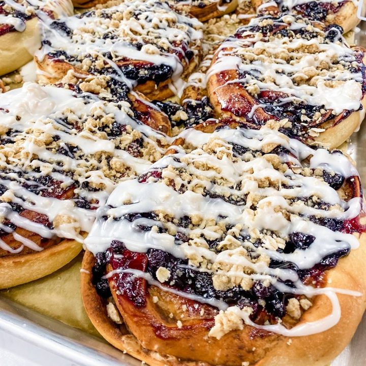 Blueberry Crumble Cinnamon Rolls with white drizzle and crumble topping
