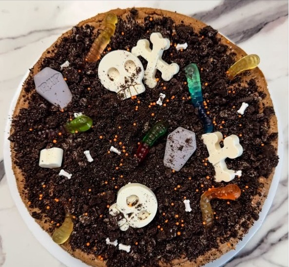 Graveyard Cheesecake with Oreo crumbs, candy skulls and bones, and gummy worms